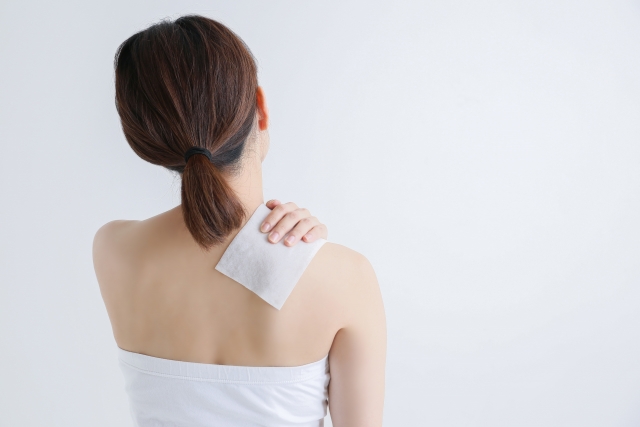 肩にシップを貼る女性